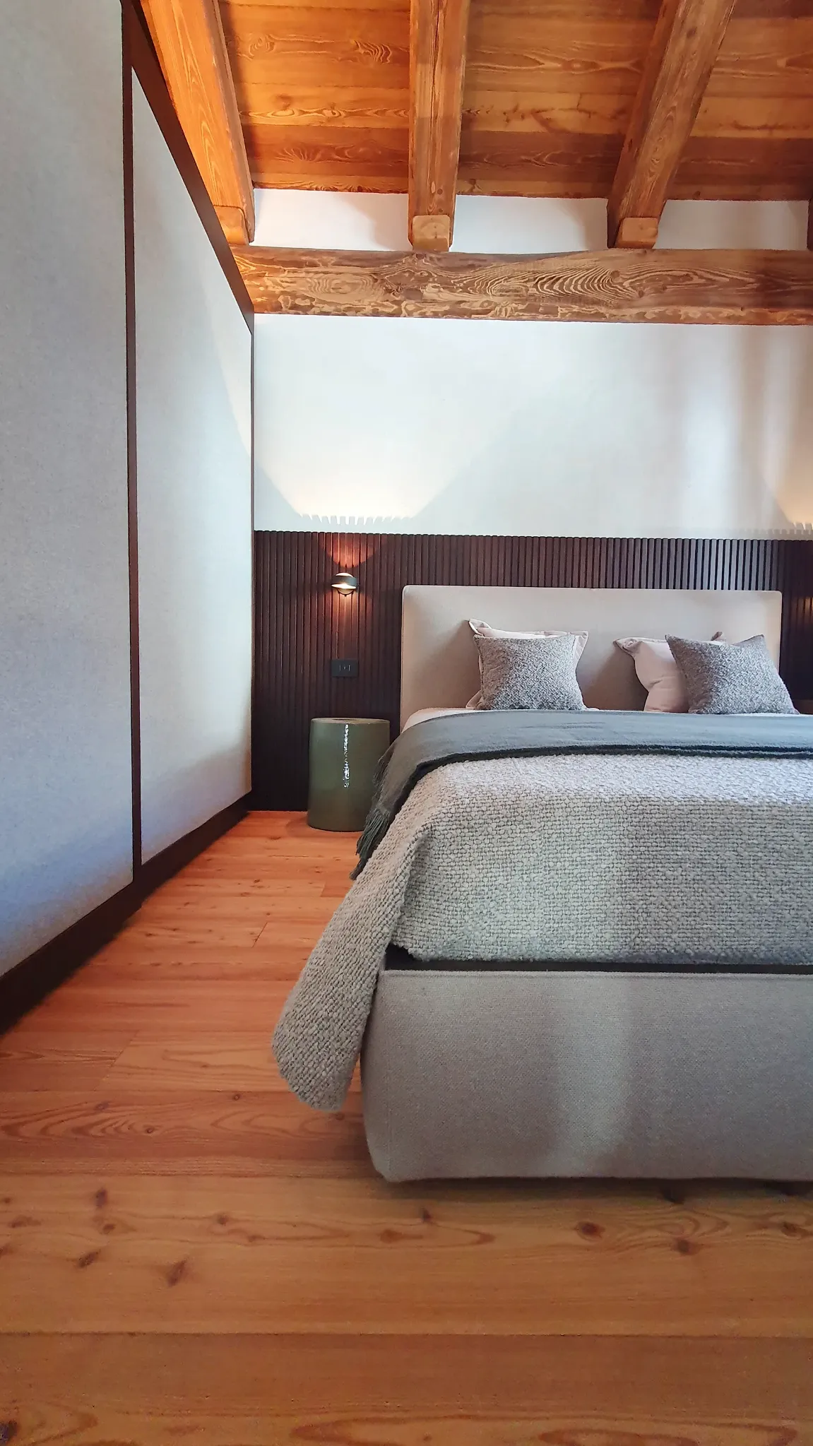 Camera da letto con boiserie verticale, travi in legno e luce integrata