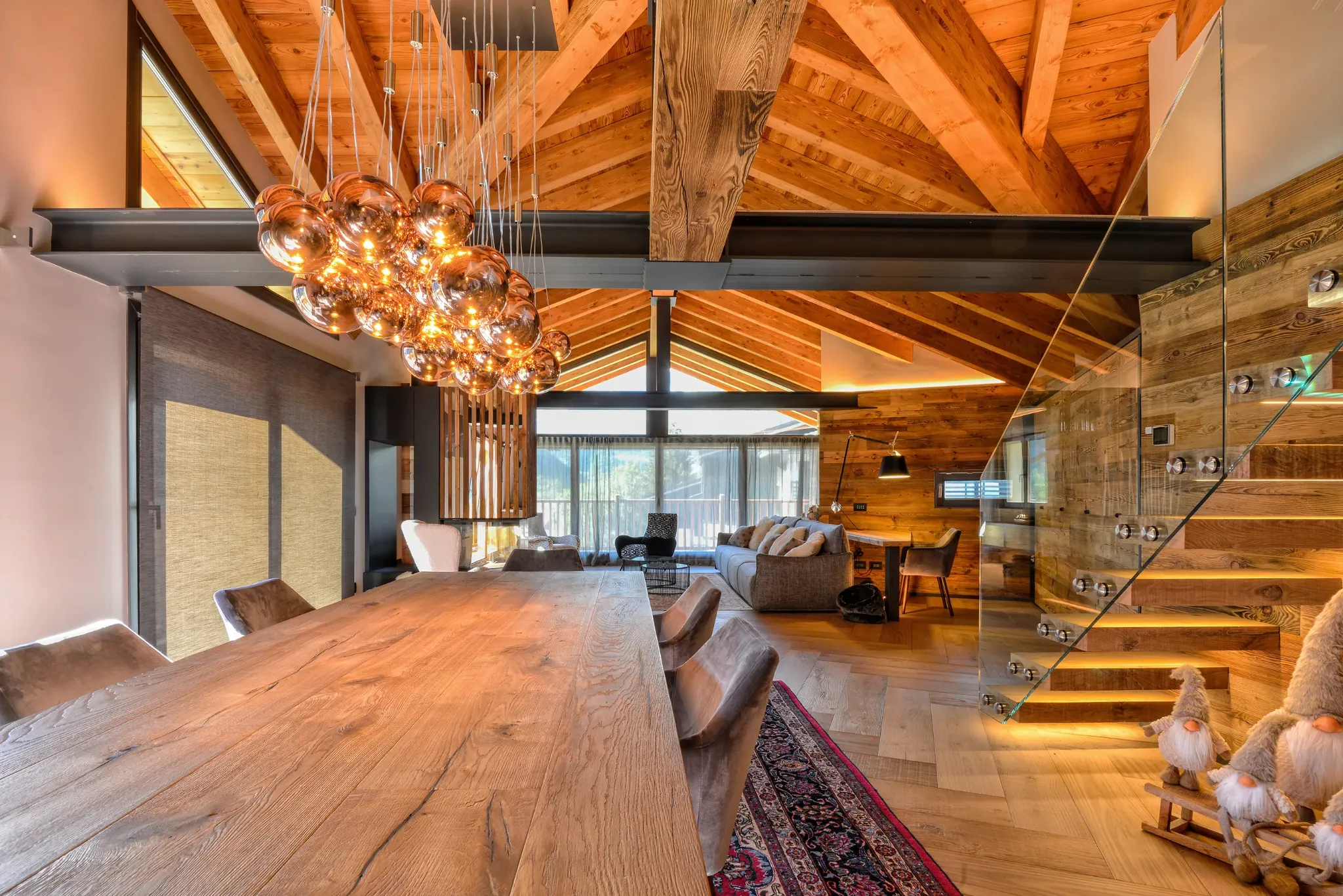 Loft con grande tavolo in legno, scala in vetro e ampia vetrata